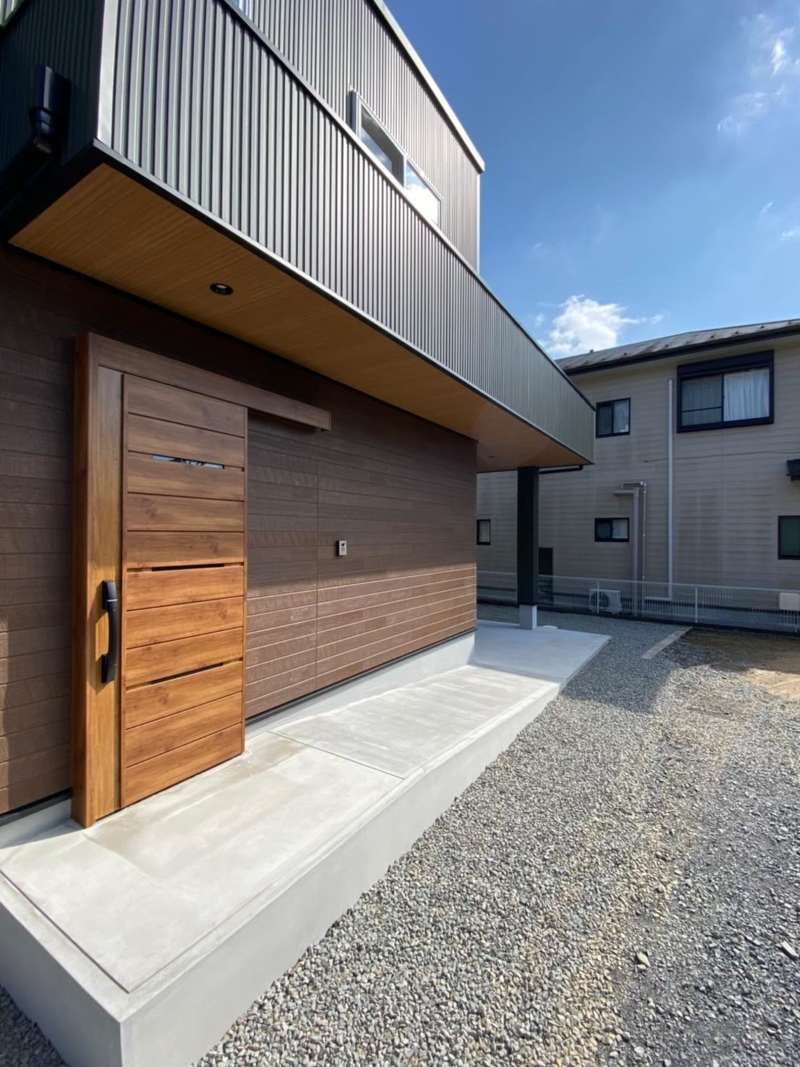 グリーンのガルバリウム鋼板の外壁材にアクセントの木目調が映える、43坪の回遊式動線のお家